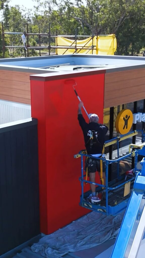 We Paint Gold Coast painter on a boom lift painting the red feature wall of the new McDonalds at Aratula