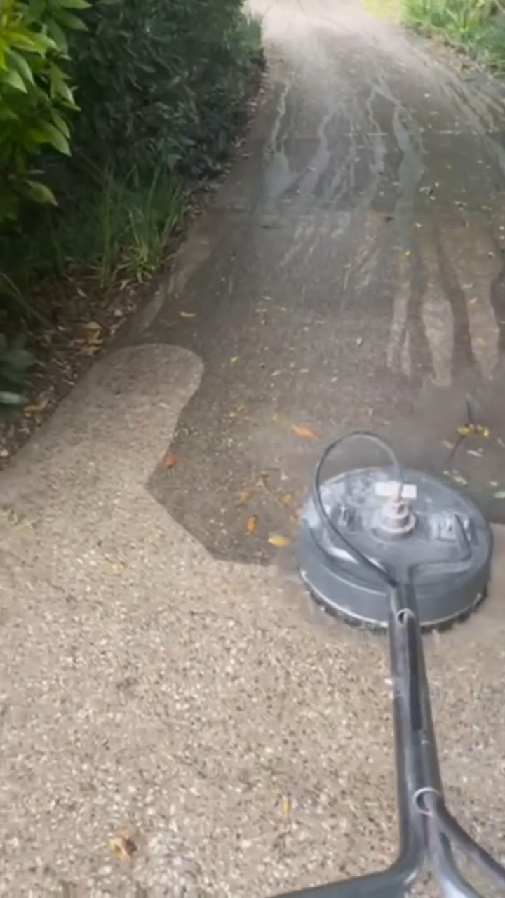 Surface cleaner pressure washing a concrete driveway, half cleaned, We Paint Gold Coast