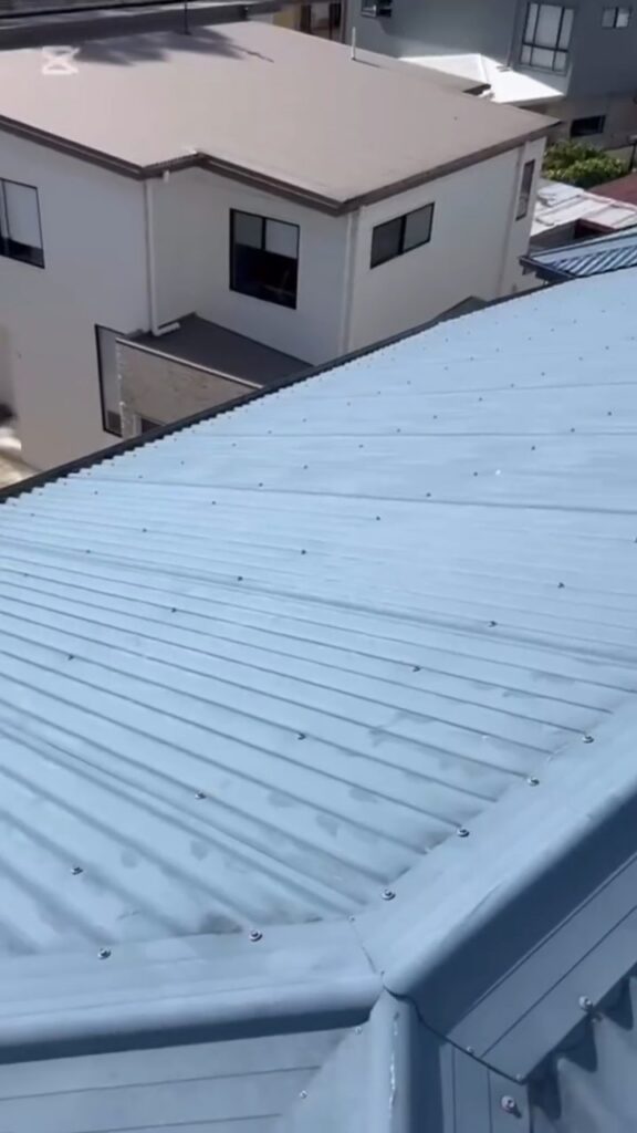 Freshly restored blue-grey metal roof on a two-storey Gold Coast home, aerial view