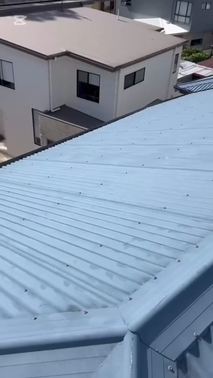 Freshly restored blue-grey metal roof on a two-storey Gold Coast home, aerial view
